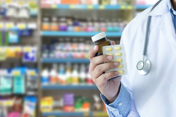 薬瓶とカプセルを手にする薬剤師の手元（調剤薬局の売却・M&A成功事例）