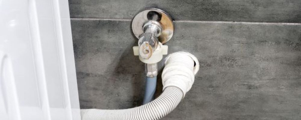 高圧洗浄用のノズルを排水管の口に挿入して配管内部を洗浄している作業の様子